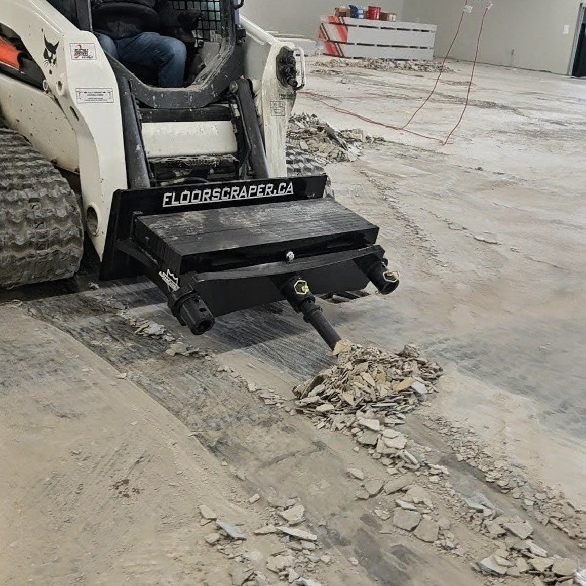 Bobcat loader with a floor scraper attachment on a concrete surface